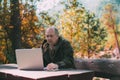 Aged hunter in autumn forest with laptop Royalty Free Stock Photo