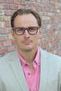 Aged imposing businessman in beige suit and pink dress shirt. Isolated on urban brick wall background