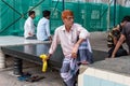 An aged Indian man with an injured hand and henna dyed hair sitting alone in the Mecca Masjid