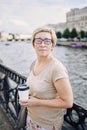 Aged lady with drink on embankment