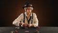 Aged lady in gangster attire expertly deals poker cards