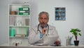 Aged male doctor reviews the patient's medical history and concentrates on the treatment options for the disease. Doc in