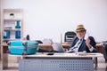 Old male employee preparing for travel in the office Royalty Free Stock Photo