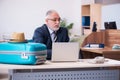 Old male employee preparing for travel in the office Royalty Free Stock Photo