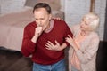 Aged man coughing near his wife
