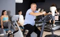 Aged man doing cardio workout on exercise bike in gym Royalty Free Stock Photo