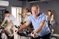 Aged man doing cardio workout on exercise bike in gym Royalty Free Stock Photo