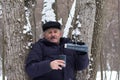 Aged man going to pour water from thermos into cup in the winter forest