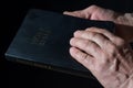 Aged man`s hands holding the Bible. Low key light. Royalty Free Stock Photo