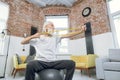 Aged man sitting on ball and training arms with rubber band Royalty Free Stock Photo