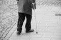 aged man walking with sticks in the street on cobblestone on back view Royalty Free Stock Photo