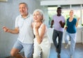 Aged man and woman dancing jive during group training