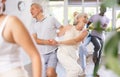 Aged man and woman dancing jive during group training