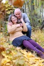 Aged man and woman hugged in the autumn park against the background of trees, the concept of a healthy lifestyle, good mood,