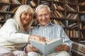 Senior couple together at home retirement concept reading book laughing Royalty Free Stock Photo