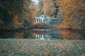 an old, run down house is reflected in the water on a fall day