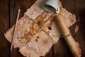 Aged parchment scroll, an old map, a pencil, and a spilled coffee cup on a wooden table. Royalty Free Stock Photo