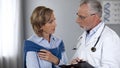 Aged physician talking to serious female patient, showing test results, medicine Royalty Free Stock Photo