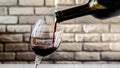 Pouring red wine into a glass on a brick wall background,close-up Royalty Free Stock Photo