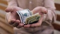 Aged retired man holding dollars in hands close-up, pension fund, bank savings Royalty Free Stock Photo