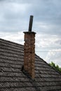 Aged roofing tiles with chimney on old house in village. A lot of moss on tiled roof of hovel against blue cloudy sky. Countryside Royalty Free Stock Photo