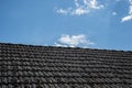 Aged roofing tiles on old house in village. A lot of moss on tiled roof of hovel against blue cloudy sky. Countryside scene Royalty Free Stock Photo