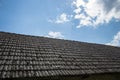 Aged roofing tiles on old house in village. A lot of moss on tiled roof of hovel against blue cloudy sky. Countryside scene Royalty Free Stock Photo