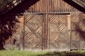 An aged, rural farm building with two doors and rusted locks with a rustic natural wooden facade and decorative woodwork Royalty Free Stock Photo