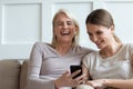 Mother and adult daughter watching funny videos on smartphone laughing Royalty Free Stock Photo