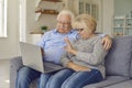 Aged senior couple waving hands greeting grandchildren through facetime using laptop. Royalty Free Stock Photo