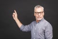 Aged senior man wearing glasses isolated against black background amazed and smiling to the camera while presenting with hand and Royalty Free Stock Photo