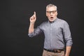 Aged senior man wearing glasses isolated against black background amazed and smiling to the camera while presenting with hand and Royalty Free Stock Photo