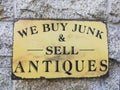 a sign that says we buy junk and sell antiques on a stone wall Royalty Free Stock Photo