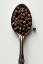 Aged Silver Spoon Filled with Whole Black Peppercorns on White Background Royalty Free Stock Photo