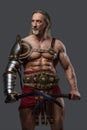 Aged but still mighty muscular gladiator with long grey hair and beard