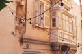 Aged stylish wooden balcony and window with shades on old residential building in downtown of Valletta, Malta Royalty Free Stock Photo