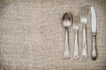 Aged vintage silver fork, knife, spoon on jute background Royalty Free Stock Photo