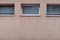 Aged weathered pink wall with three windows with blinds texture detail urban sighing with lots of copy space for text