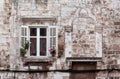 Aged windows and flower boxes of historical building from old town of Pula, Croatia / Detail of ancient venetian architecture.