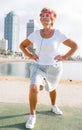 Aged woman doing fitness moves on beach