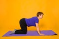 Aged woman doing yoga on a purple rug. Studio photo on a yellow background Royalty Free Stock Photo