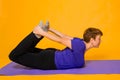 Aged woman doing yoga on a purple rug. Studio photo on a yellow background Royalty Free Stock Photo