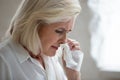 Aged woman holding napkin blows runny nose need antiviral medication
