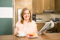 Aged woman reading and eating breakfast Royalty Free Stock Photo