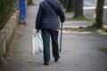 aged woman walking with stick in the street  on back view Royalty Free Stock Photo