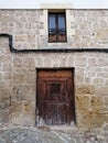 Aged wooden door in stone facade with exposed cables