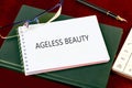 AGELESS BEAUTY text written on a blank page of a notebook on a green notebook Royalty Free Stock Photo