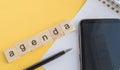 Agenda plan written on wooden cubes on desktop with pen  phone and paper Notepad on yellow background  top view  flat layout Royalty Free Stock Photo