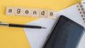 Agenda plan written on wooden cubes on desktop with pen  phone and paper Notepad on yellow background  top view  flat layout Royalty Free Stock Photo