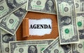 Agenda symbol. The concept word `agenda` appearing behind torn brown paper. Dollar bills. Business and agenda concept. Copy spac Royalty Free Stock Photo